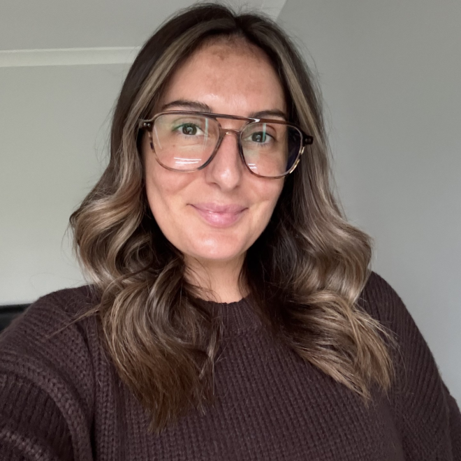Woman in glasses looking at camera standing in room