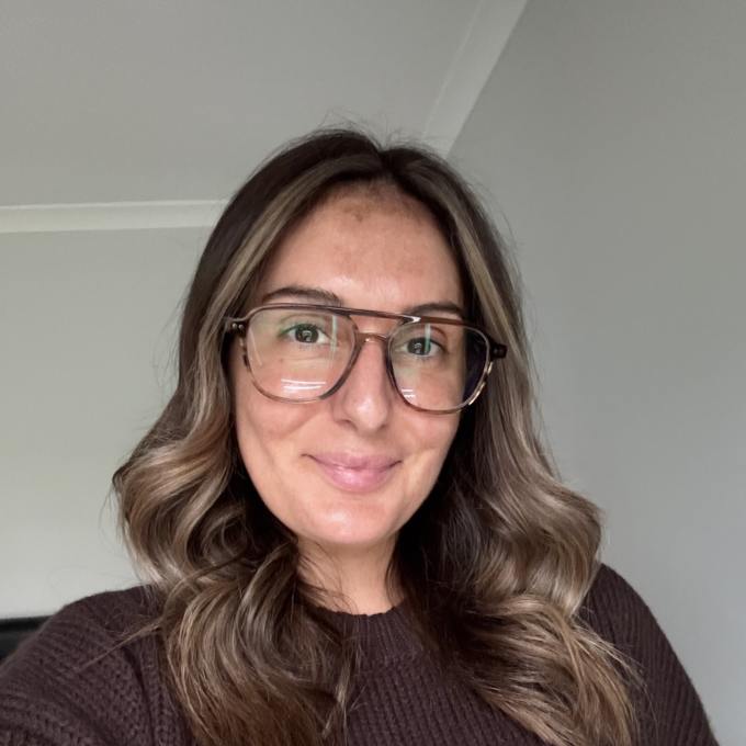 Woman in glasses looking at camera standing in room