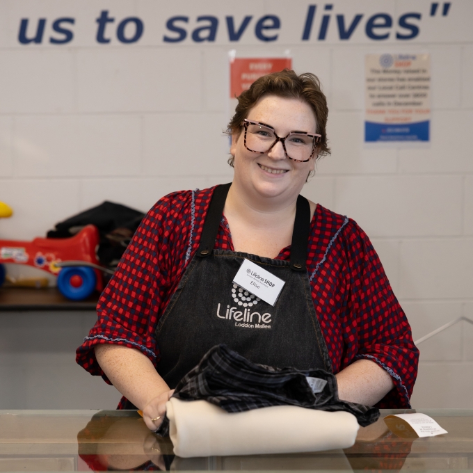 Lady working at thrift store folding clothes at counter
