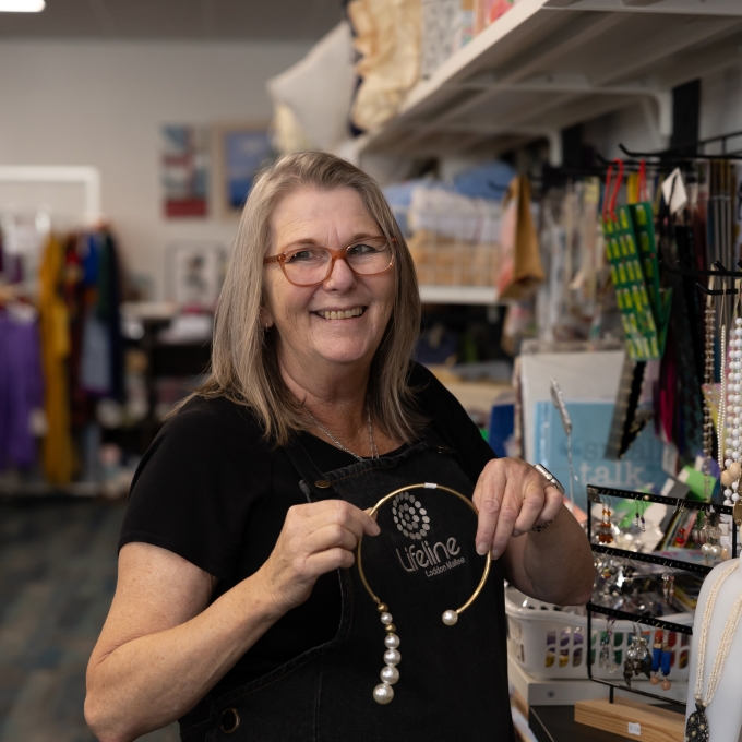 Woman working at thrift store showing off jewellery