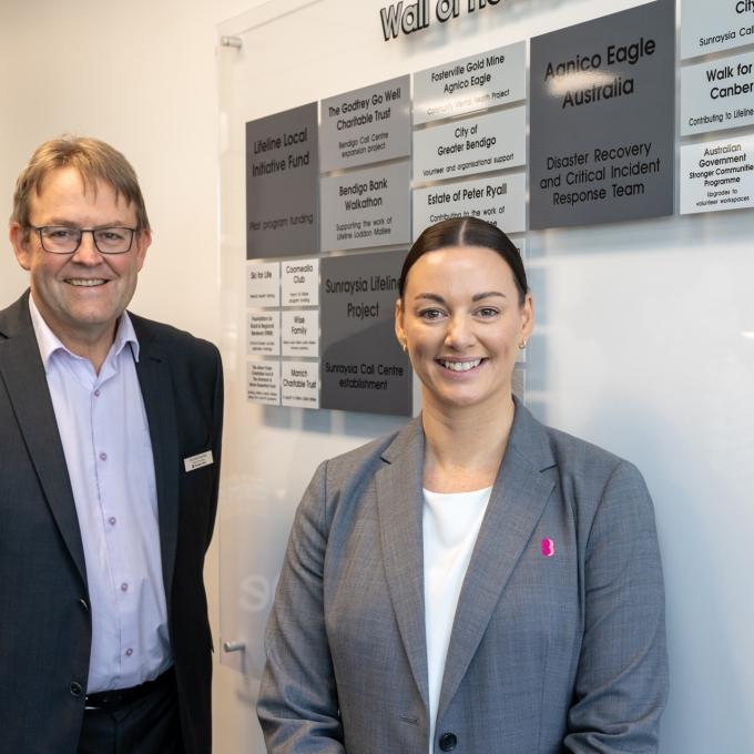 Man and woman looking at camera in front of donor wall
