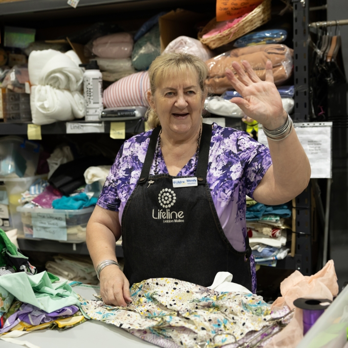 Woman in thrift store donation collection waving to camera