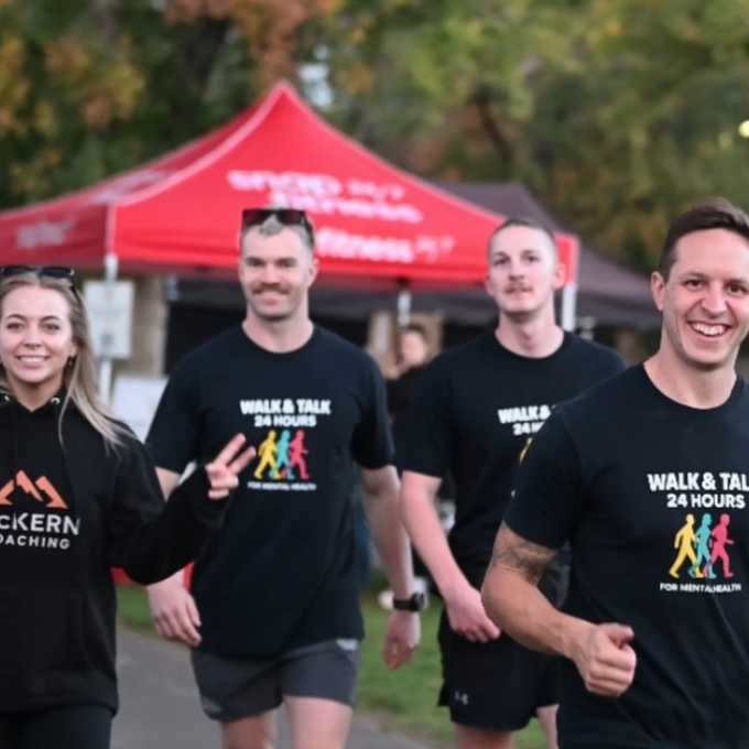 Four people in Walk and Talk t-shirts walking down track